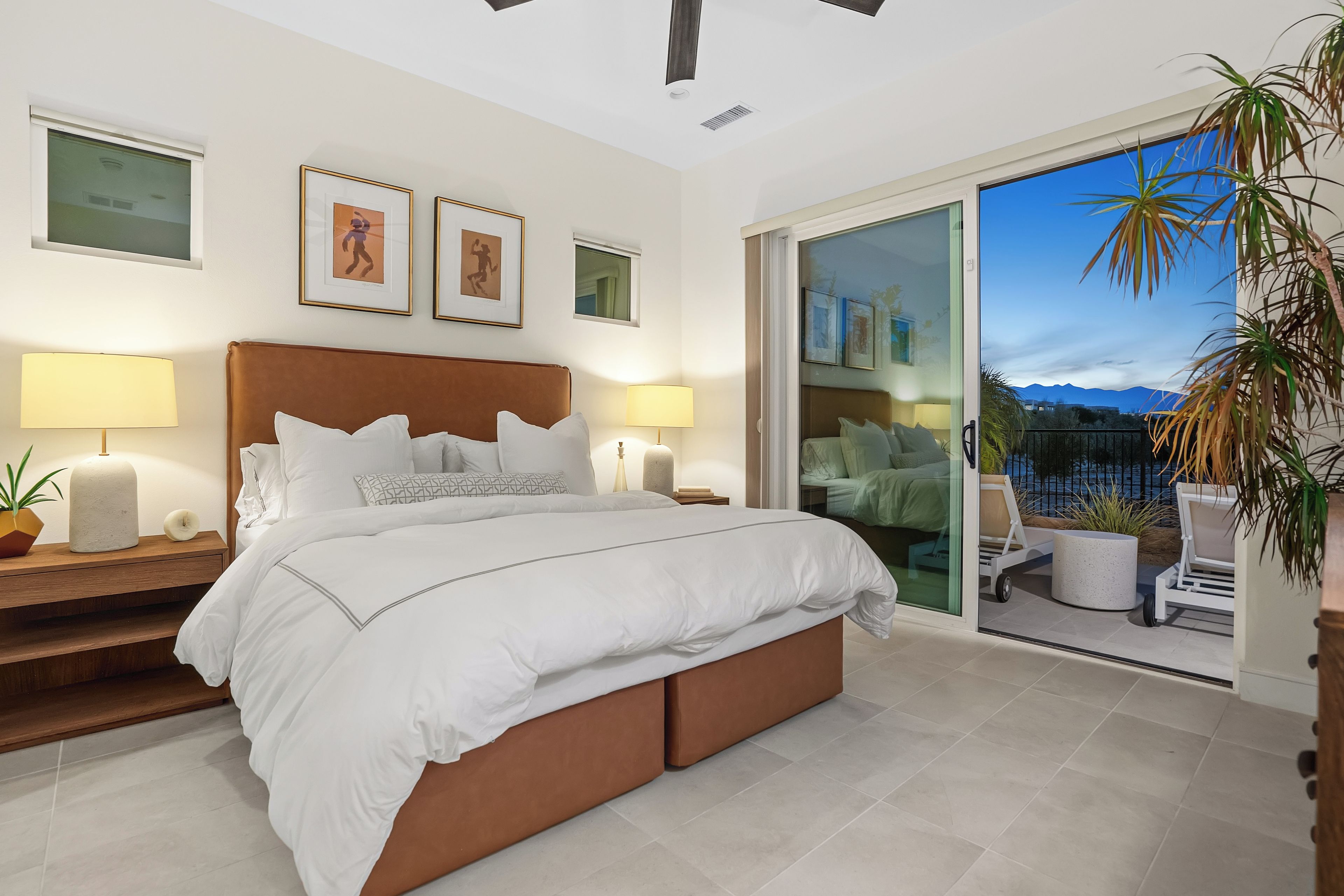 Un dormitorio moderno con una cama grande, dos lámparas de noche, una mesita de noche y vistas al exterior a través de un ventanal corredero.