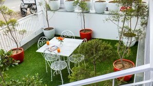 A rooftop terrace with a white table and chairs, surrounded by potted plants and a small garden area. - Hotel Golden Key  (New Delhi)