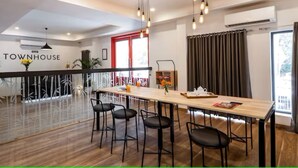 A modern hotel lobby with a long wooden table, black chairs, and a red-framed window. - Hotel Golden Key  (New Delhi)
