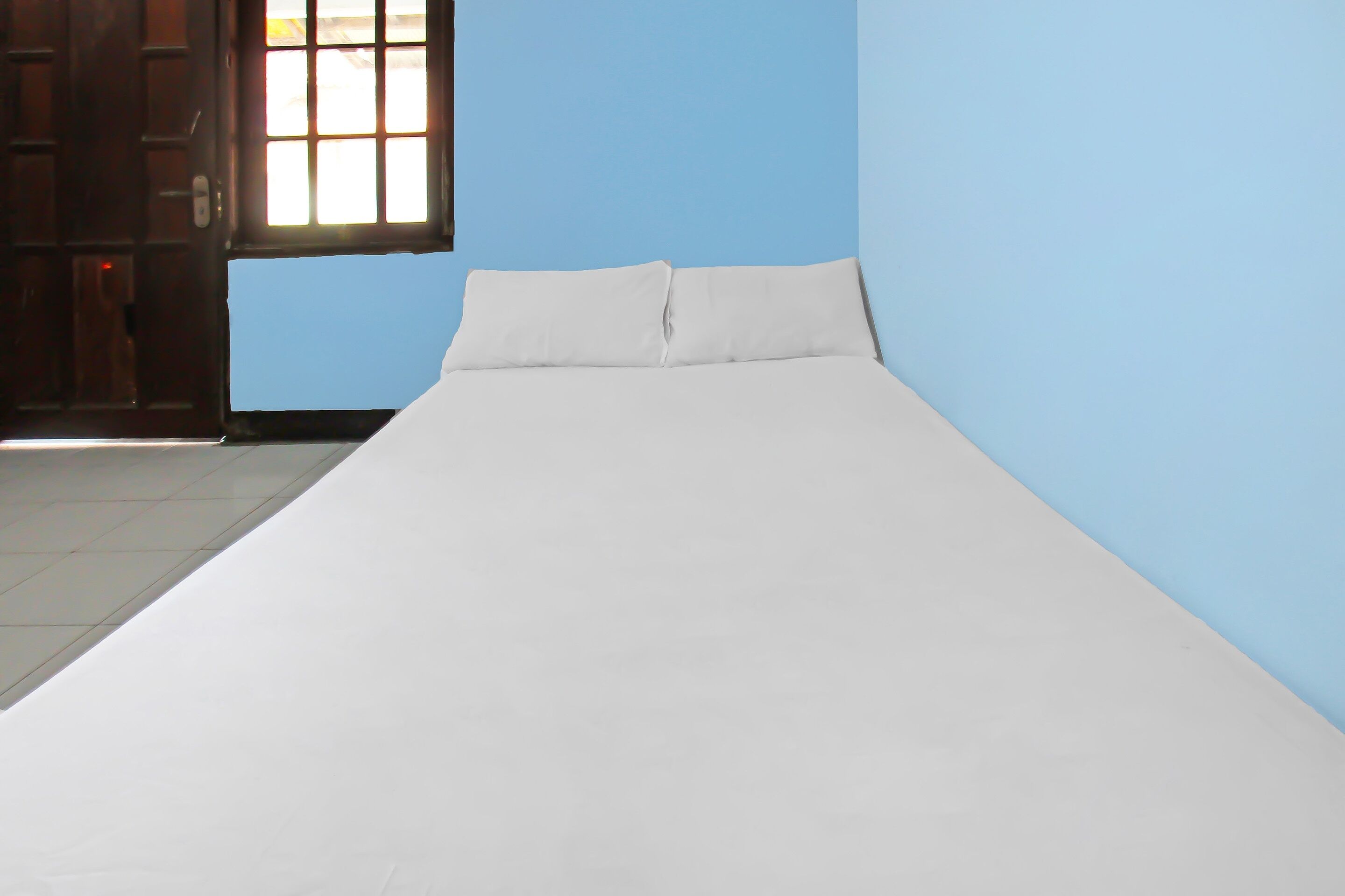 Ein Bett in einem Zimmer mit blauen Wänden und einem Fenster.