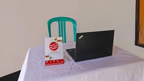 A laptop on a table with a sign about the OYO app. - Hotel O Sukandi Homestay Near The Semeton Homestay (Janapria)