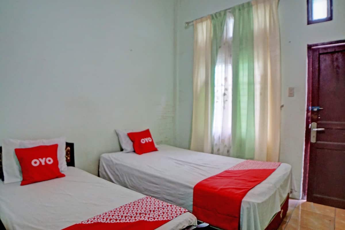 A room with two beds, each with a red and white bedspread and a pillow with "OYO" on it.