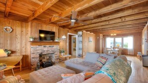 Interior acogedor de una cabaña de troncos con chimenea, televisión y un sofá grande.