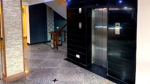 An elevator area with a modern design, including a marble floor and a glass partition. - Hotel Avkaash  (Ambala)