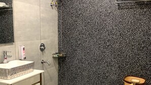 A bathroom with a white sink, a toilet, and a shower with a water heater. - Hotel Avkaash  (Ambala)