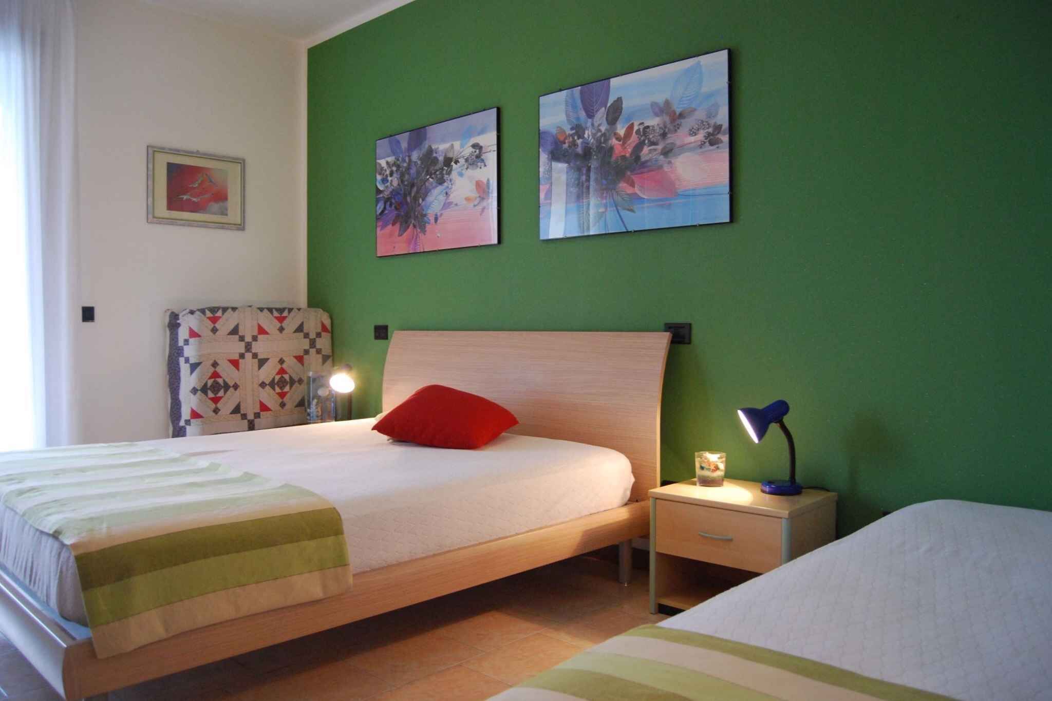 A bedroom with a bed, a nightstand, a lamp, and two wall-mounted paintings.