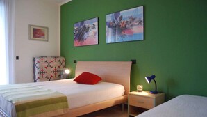 A bedroom with a bed, a nightstand, a lamp, and two wall-mounted paintings.