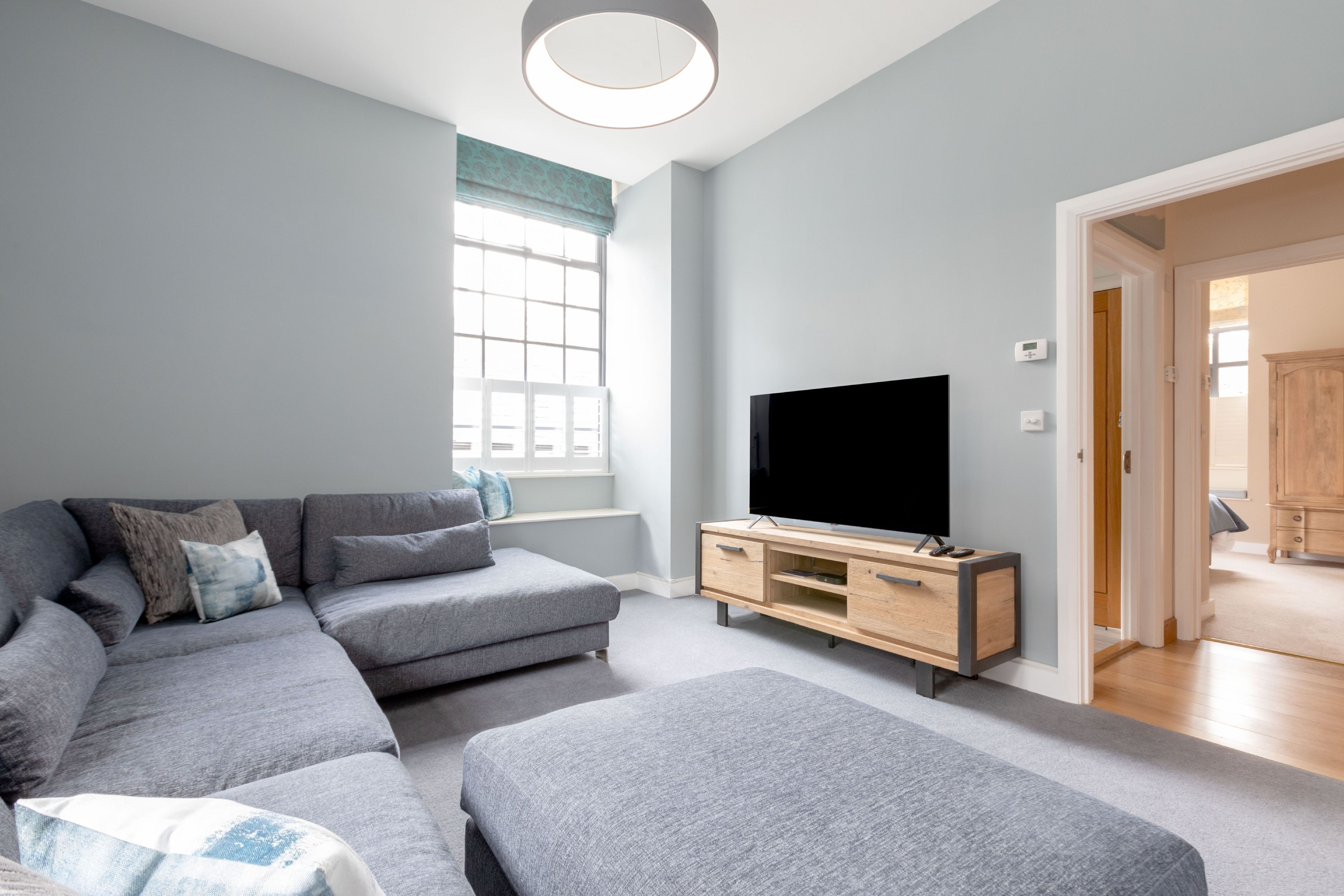 Een moderne woonkamer met een modulaire bank, een flatscreen televisie en een houten tv-meubel.