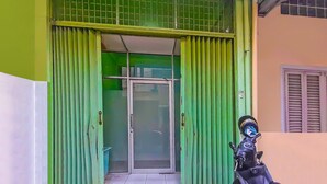 A green door with a glass panel and a motorcycle parked outside.