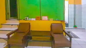 A waiting area with two chairs, a window with green blinds, and a counter with a sign.