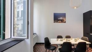 A dining area with a table set for six, black chairs, a white tablecloth, and a cityscape painting on the wall. - La Residenza Delle Vigne by Wonderful Italy (Genoa)