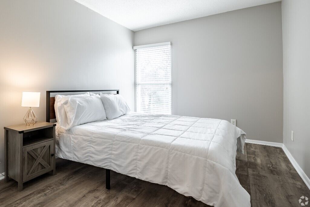 A bedroom with a bed, nightstand, and window.