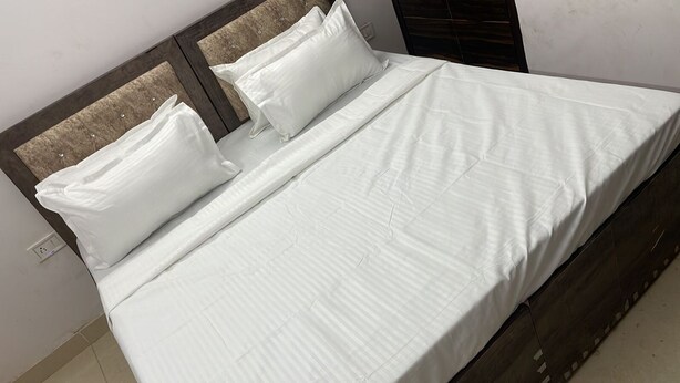 Una cama bien tendida con sábanas blancas y cabecera de madera.