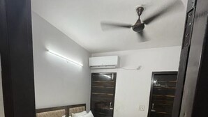 Un dormitorio con cama, ventilador de techo, aire acondicionado y armario.