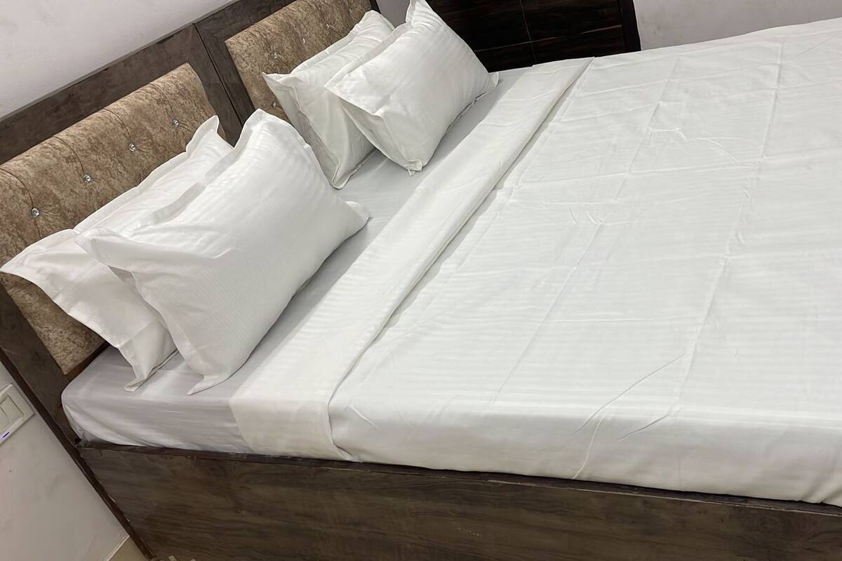 Un lit bien fait, avec du linge de lit blanc et des oreillers, une tête de lit en bois et un cadre en bois.