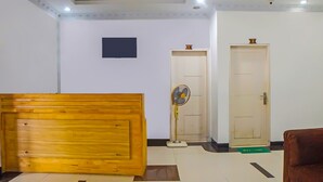 A reception area with a wooden reception desk, a standing fan, and two doors. - Hotel O Medan City Near Sun Plaza Formerly 99 Residence (Medan)