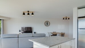 Una cucina moderna con un divano grigio, una televisione, una sveglia e un'area pranzo.