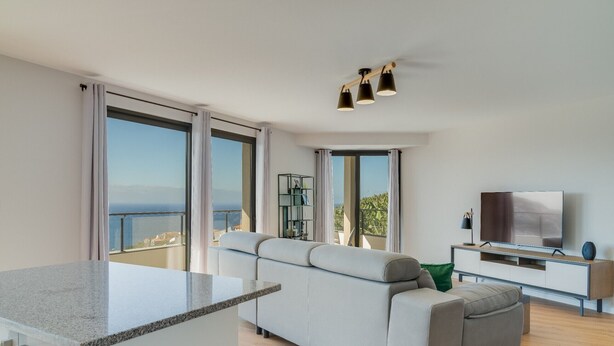Un soggiorno moderno con divano, televisore e balcone con vista.