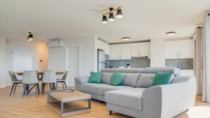 Un soggiorno moderno con un divano ad angolo grigio, un tavolino in vetro e una zona pranzo con sedie.
