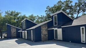 A row of blue houses with stone walls and white doors, set in a sunny outdoor area. - Walk to the Strip! Calm Cove Swimming, Sun Decks & Prime Lake Location (Lake Ozark)