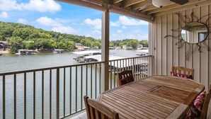 A wooden table and chairs on a balcony overlooking a lake with boats and docks. - Stunning Views, Inviting Pools, and Endless Fun! (Osage Beach)