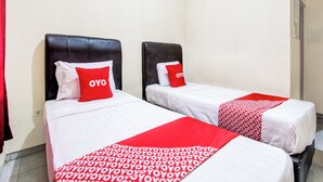Two single beds with black headboards and red pillows, white bedsheets, and a red and white patterned blanket. - Super OYO 92511 Griya Dias  Syariah (Yogyakarta)