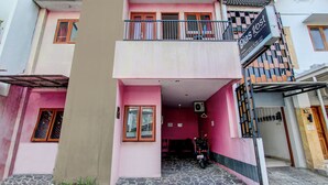 A multi-story building with a pink facade, a balcony with a metal railing, and a sign for 'Windsor Kost Exclusive'. - Super OYO 92511 Griya Dias  Syariah (Yogyakarta)