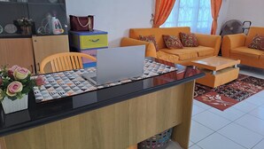 A modern living room with a glass-top coffee table, a laptop, and a sofa set. - Hotel O Safira Guest House Danau Ranau (Muaradua)
