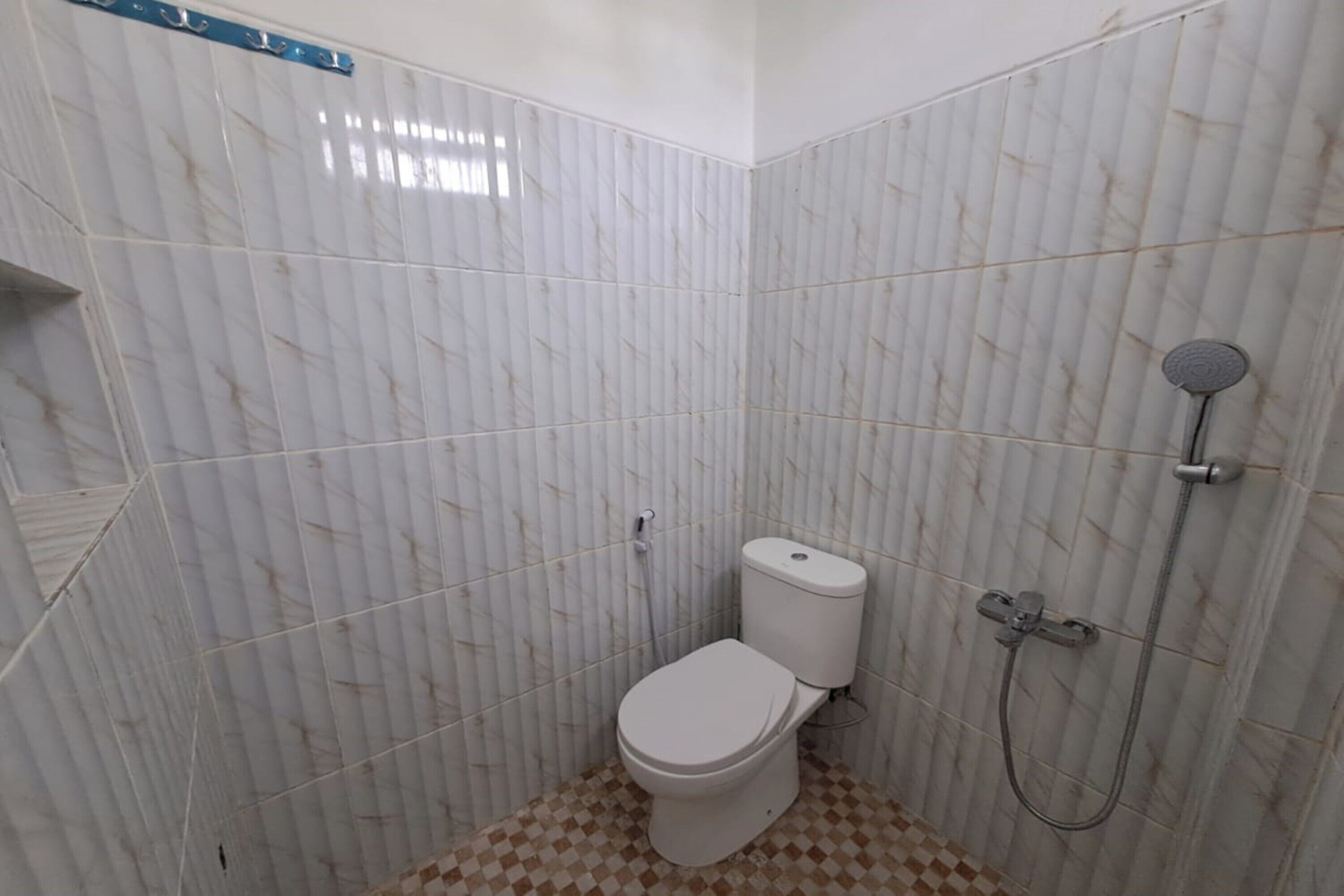 A small, compact bathroom with a toilet, a shower, and tiled walls.