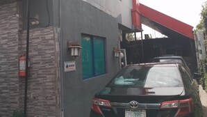 A modern building with a car parked in front. - Tega Suites Ikeja (Lagos)