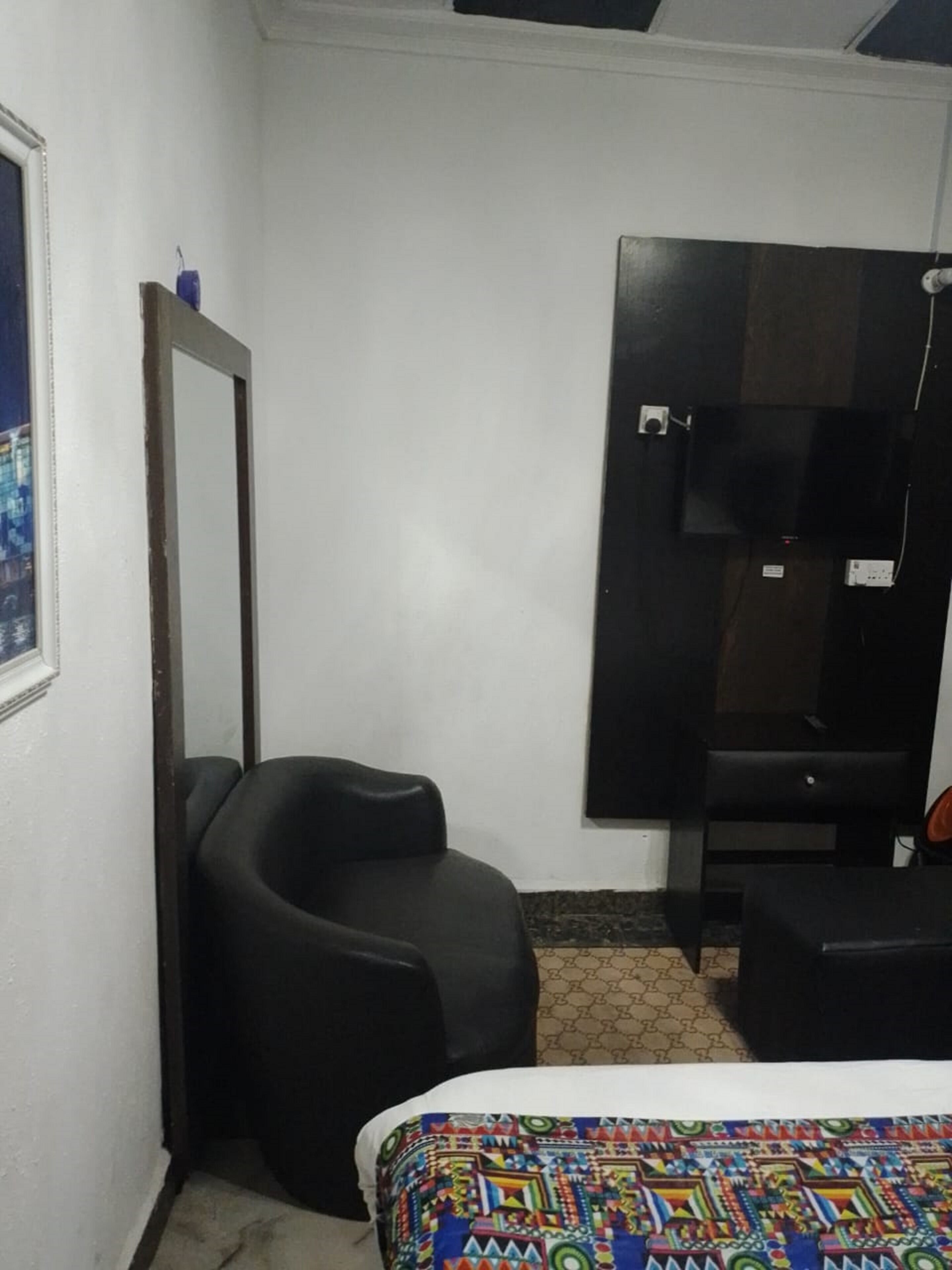 Una habitación pequeña y sencilla con cama, escritorio, silla, espejo y armario.