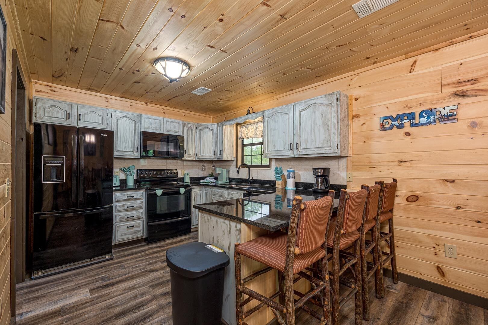 A compact kitchen with wooden cabinets, a black refrigerator, a microwave, and a coffee maker.