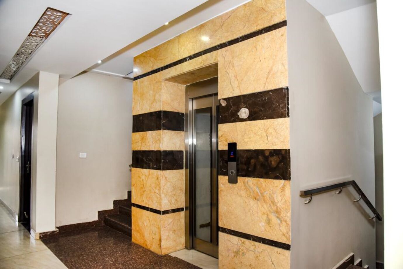 Un moderno ascensor con paredes de mármol y panel de control digital.