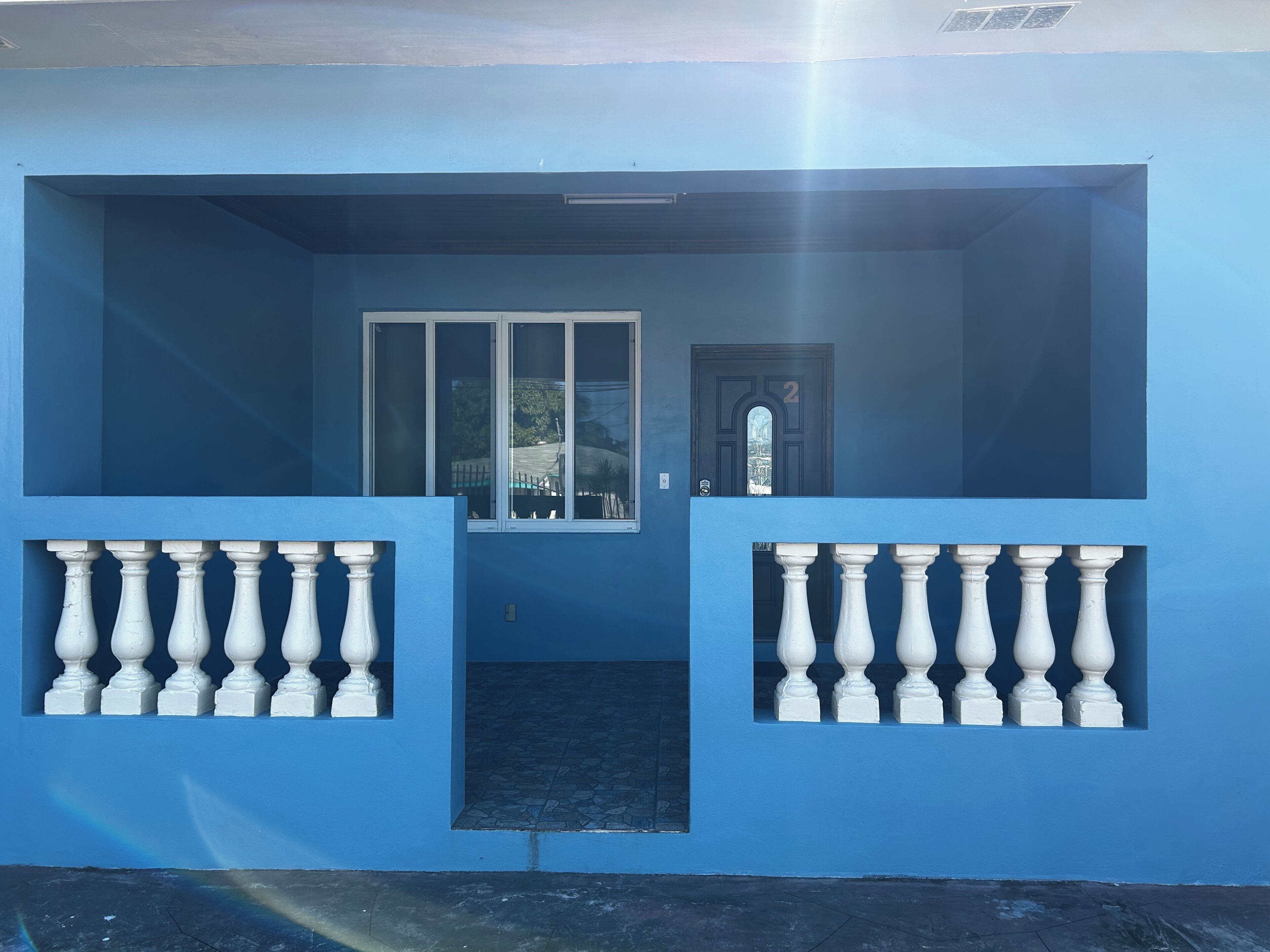 Een blauw gebouw met een balkon, een deur en een raam.