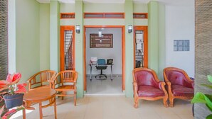 A room with a wooden table and chairs, a desk with a chair, and a door with a number sign. - Hotel O Wisma Bambu Syariah (Bandar Lampung)