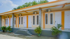 A hotel with multiple rooms, each with a door and window, and a covered outdoor area with steps leading to the entrance. - Hotel O Wisma Bambu Syariah (Bandar Lampung)