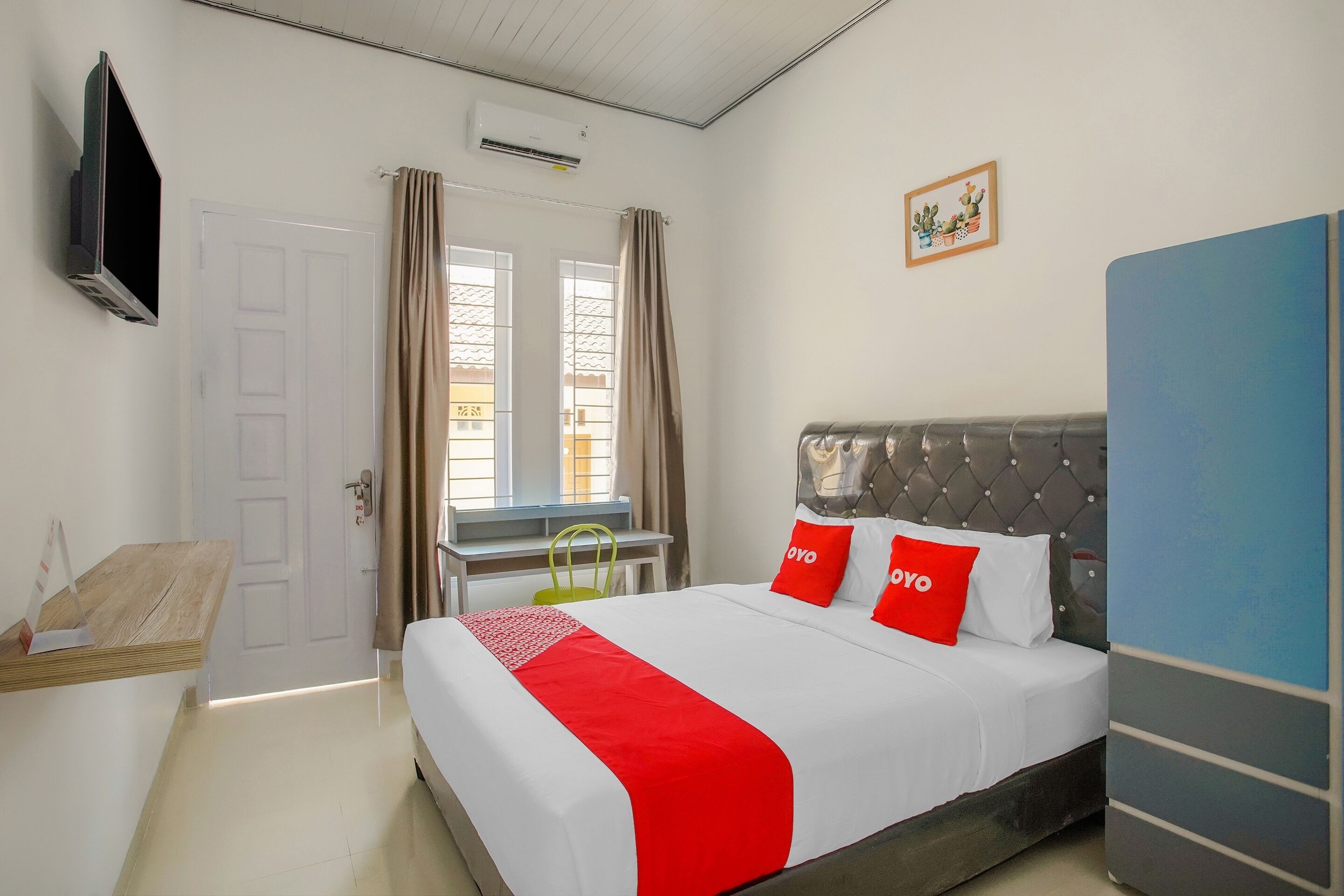 A hotel room with a bed, a desk, a TV, and a window with curtains.