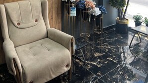 Un intérieur moderne avec un fauteuil beige, une horloge en forme de carte du monde et une vue sur la rue.