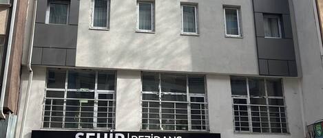 Un immeuble à plusieurs étages dont la devanture porte l’inscription « SEHIR REZIDANS ».