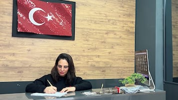 Une personne est assise à un bureau dans une pièce dont un mur est en bois et où est accroché un drapeau encadré.