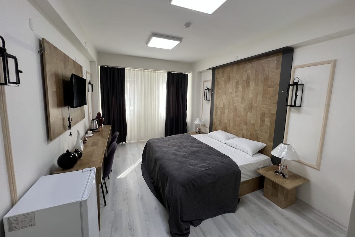 Une chambre d’hôtel moderne équipée d’un lit, d’une table de chevet, d’une lampe et d’un bureau avec une chaise.