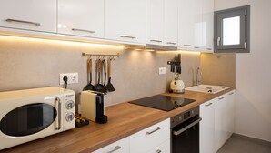 Een moderne keuken met witte kasten, een houten aanrecht, een ingebouwde magnetron, een waterkoker en een spoelbak.