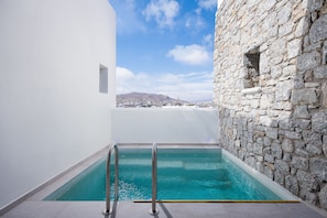 A swimming pool with stone walls and a clear view of a distant town.