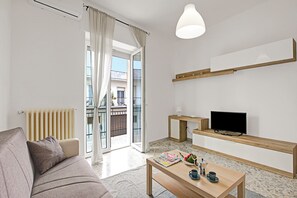 A modern living room with a sofa, coffee table, TV, and a balcony view. - Casa Ojala' in the Center of Alberobello (Alberobello)