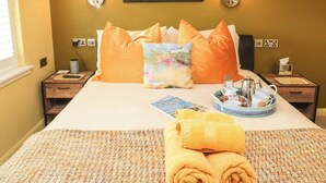 Une chambre d’hôtel avec un lit, deux tables de chevet, un tableau encadré au mur et une fenêtre avec des stores.