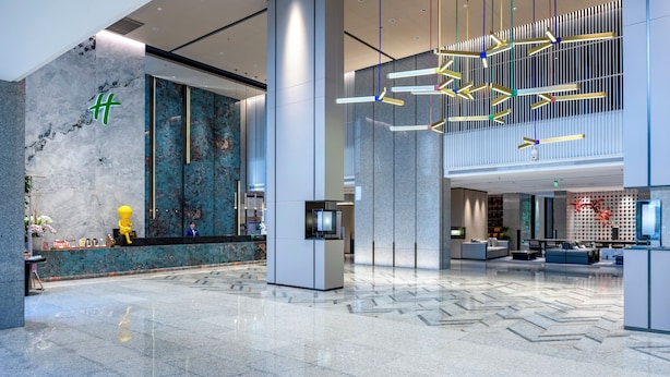 A modern lobby with a marble reception desk, a seating area with sofas, and a large digital screen. - Holiday Inn Wuyi Mountain Water Village by IHG (Nanping)