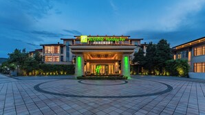 A hotel entrance with a modern design, featuring a prominent entrance canopy and illuminated signage. - Holiday Inn Wuyi Mountain Water Village by IHG (Nanping)