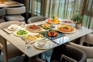 Una mesa de comedor dispuesta con varios platos, incluyendo mariscos, verduras y un postre.
