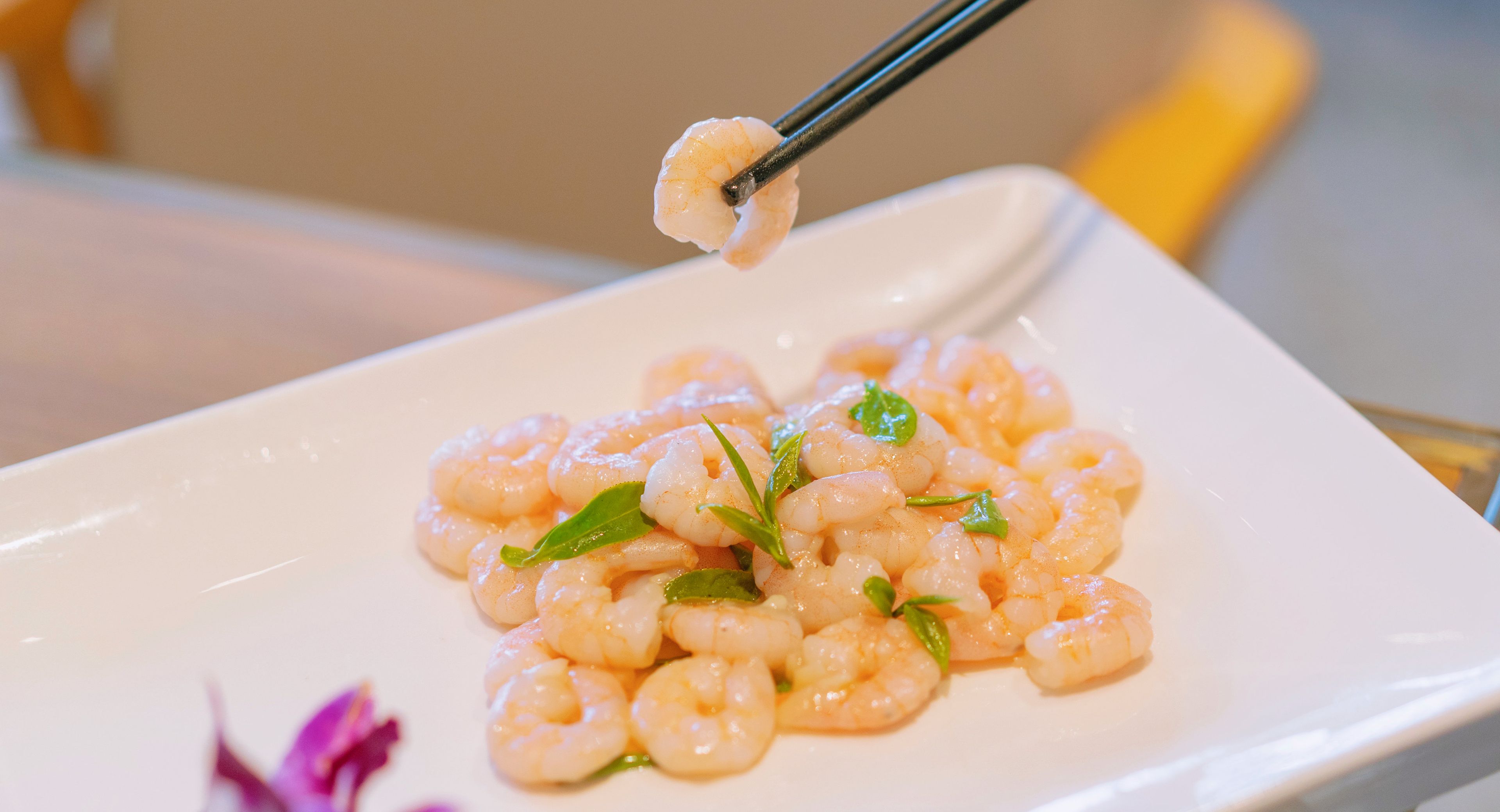 A plate of cooked shrimp garnished with green leaves.