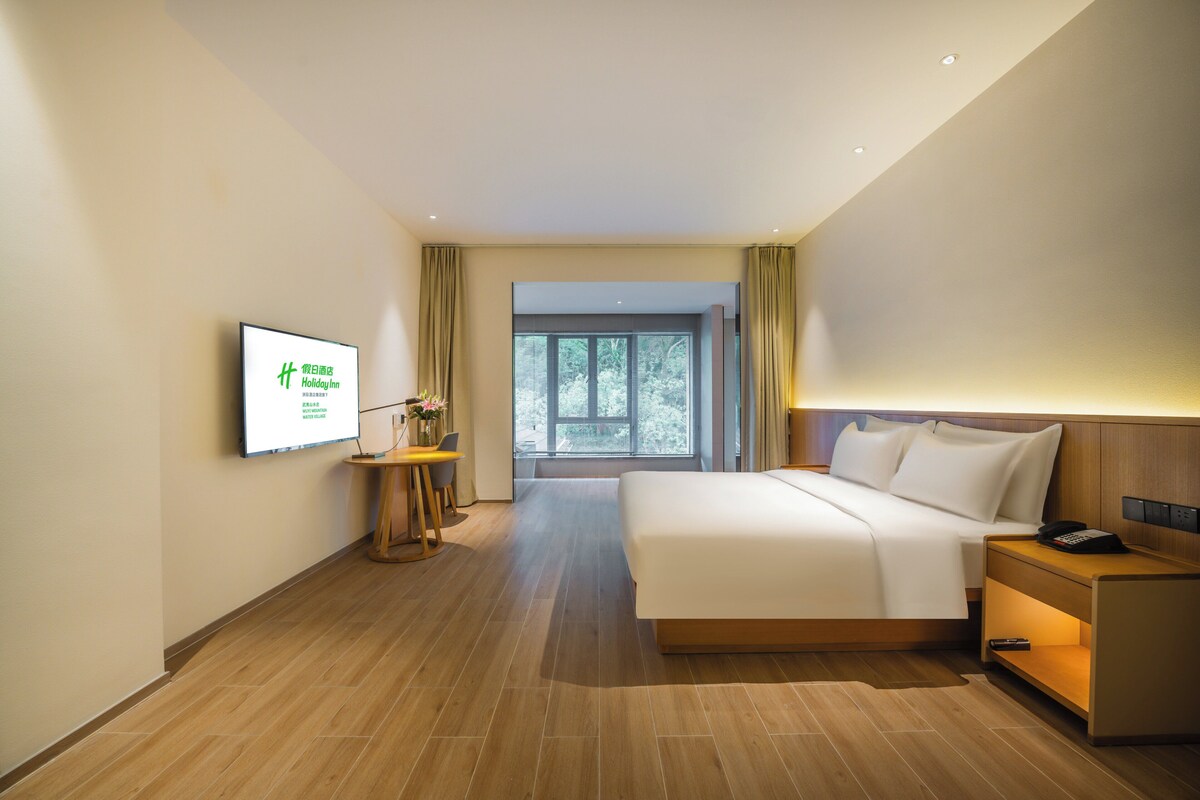 Habitació d'hotel amb llit, taulell de nit, làmpada i televisor que mostra informació de l'hotel.